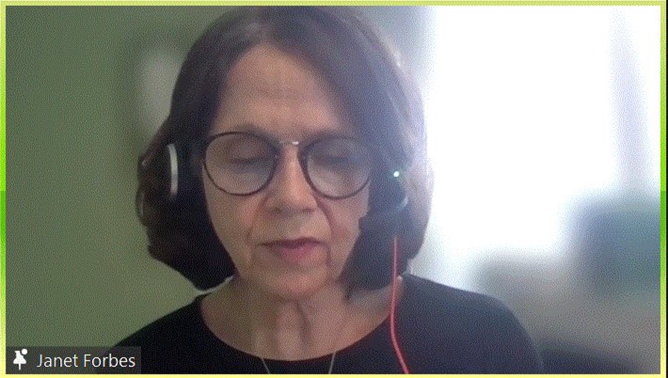 Janet Forbes speaking into a headset while looking at the camera on a Zoom call. 