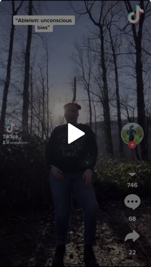 Description du visuel de la vidéo Tik Tok intégrée:  Une femme à double chignons roses se tient debout, confiante, dans les bois.  Elle fait face à la caméra, rétroéclairée par les rayons du soleil.  Dans le coin supérieur gauche est écrit: « Capacitisme : préjugé inconscient. »  
 
