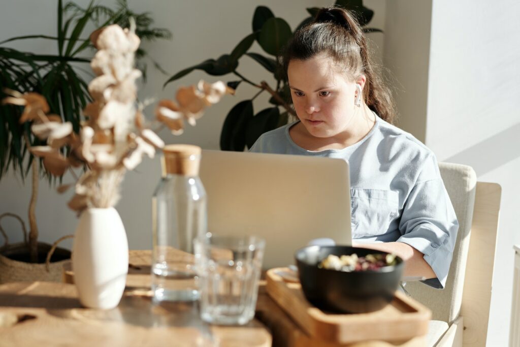 A person with a visible intellectual disability using a laptop